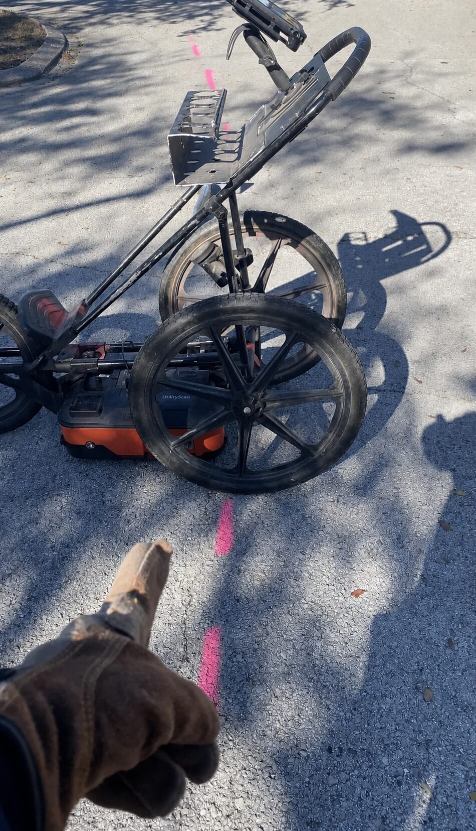 Ground penetrating radar cart positioned over pink utility route marks on pavement